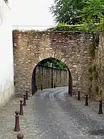 Arche en pierres appareillées, surmontant une rue pavée étroite.