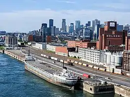 Vue aérienne sur le port de Montréal. Au premier plan : navire accosté au quai. En arrière plan : les gratte-ciels du centre-ville.