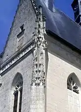 Vue d'un contrefort d'église surmonté d'une décoration de volutes.