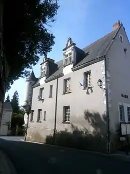 Photographie en couleurs d'un bâtiment à étage orné des drapeaux européen et français et pourvu à l'un de ses angles d'une tourelle en encorbellement.