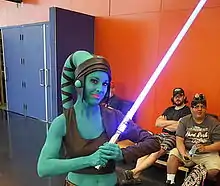 Femme maquillée entièrement en bleu avec un sabre.