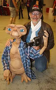 Personnage fictif E.T. et Steven Spielberg accroupi à ses côté.