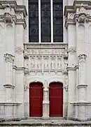 Vue de la façade d'une église, de son portail à deux battants et de la verrière qui le surmonte.