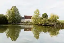 Photographie en couleurs d'un plan d'eau avec au second plan un bâtiment.