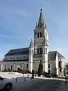 photographie en couleurs d'une église dominée par son haut clocher
