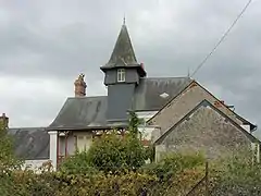 Photographie en couleurs d'une maison dont a toiture est surmontée d'un clocheton en ardoises.