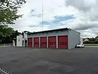 Photographie en couleurs d'un grand garage fermé par cinq hautes portes peintes en rouge.