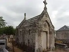 Photographie en couleurs d'une chapelle en pierre entourée de tombes, dans un cimetière.