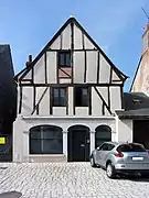 Photographie en couleurs d'une maison dont la partie supérieure du pignon est faite de colombages.