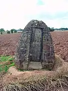 Photo d'une structure conique massive en pierre se dressant devant un champ labouré