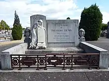 Un monument dans un cimetière, orné d'une statue et d'une plaque commémorative.