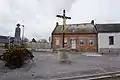 Place du village avec monument aux morts et croix de chemin.