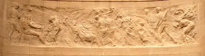 Frise en bas relief montrant des soldats et un homme blanc face à des indigènes noirs.)