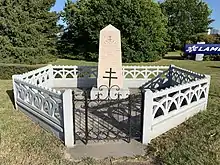 Monument blanc de la Résistance, entouré d'une clôture en béton blanc et dont l'accès se fait par un portillon noir surmonté d'une croix de Lorraine.