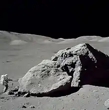 L'astronaute Harrison Schmitt se tenant debout à côté du rocher dénommé « Tracy's rock » durant la troisième sortie extravéhiculaire de la mission Apollo 17.