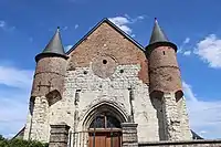 Deux échauguettes en brique supportées par des contreforts en pierre calcaire et percées de meurtrières protègent l'entrée de l'église.