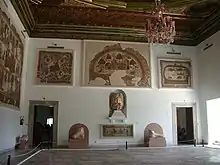 Vue d'une salle munie d'un plafond décoré et contenant des objets anciens, sculptures et mosaïques au sol et aux murs
