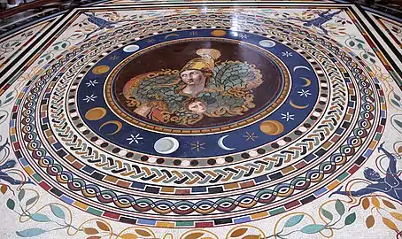 Mosaïque colorée composée de motifs circulaires, au centre la figure d'Athéna casquée surplombe le masque de Méduse.
