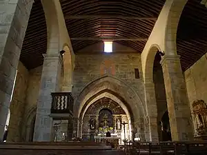 Intérieur d'une nef d'église en pierre mais couverte d'une charpente.