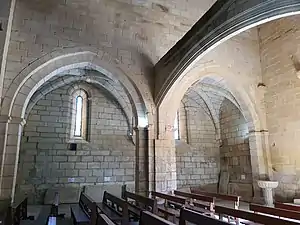 Photographie d'une nef dont la première travée est soutenue par un arc, et d'un bas-côté.