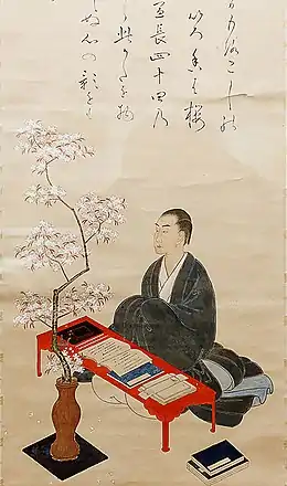 Dessin couleur. Homme en habits traditionnels sombres à une table basse avec documents. Devant arbuste dans un vase.