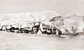 Photo en noir et blanc d'une montagne couverte et entourée de glaciers.