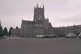 Photographie en noir et blanc d'une église néogothique en pierres dotée d'une tour-clocher massive.