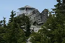 Une tour de vigie blanche au-dessus d'une falaise rocheuse.