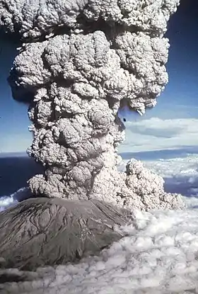 Photographie couleur d'un volcan en éruption libérant un panache de fumée massif.