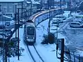 Un TGV Duplex quitte Moûtiers et monte vers Bourg-Saint-Maurice dans un paysage sous la neige.