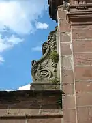 Volute en pierre blanche sur un portail en grès rose du XVIIIe siècle (abbaye de Moyenmoutier, Vosges.