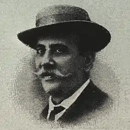Un homme avec un chapeau et une fine moustache est dessiné de trois-quarts face.