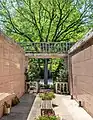 Un columbarium, derrière un frêne, au cimetière de Mount Auburn. Juillet 2022.