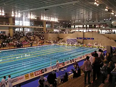 Le bassin olympique et, au sommet des escaliers, le bassin ludique. Au dernier étage de la façade, les salles de l'entreprise de musculation et fitness.