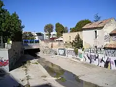 Le Verdanson vu en aval du Stade Philippidès à l'automne. On aperçoit la rue Croix-Catelan sur le pont où circule une rame de la ligne 1 du tramway de Montpellier.