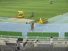 Deux athlètes en train de courir côte à côte sur une piste d'athlétisme.