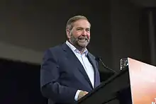 Thomas Mulcair à Ottawa derrière un pupitre aux couleurs du NPD