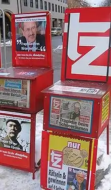 deux présentoirs à journaux rouges dans une rue