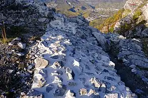 Intérieur d'un mur en pierre détruit. Il est assez large et plusieurs pierres ressortent du mortier.