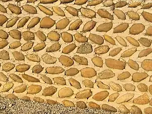 Mur en galets disposés en arête-de-poisson.