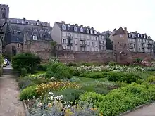 Vue générale d'un jardin et à l'arrière-plan une muraille et des bâtiments