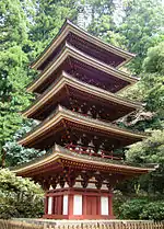 Wooden five-storied pagoda with white walls and red beams.