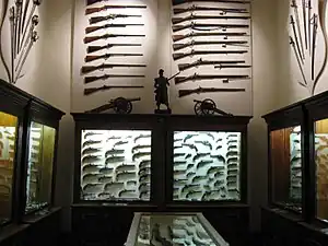 Salle des armes avec des fusils, des pistolets et des sabres.