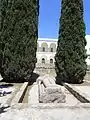 Vue d'une statue allongée avec une épée et un édifice à colonnade à l'arrière-plan.