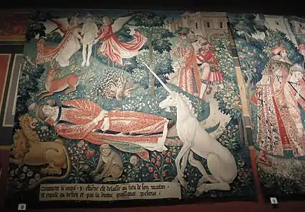 tapisserie ancienne et colorée de rouge, vert, bleu et blanc : un homme est couché dans un jardin et entouré notamment d'une licorne assise, d'un singe, d'un lion, d'un cerf et d'un porc-épic.
