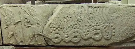 Photo d'une pierre sculpté, sur la gauche des guerriers avec des lances, sur la droite un grand serpent