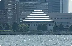Photo d'un bras de mer sur fond d'immeubles devant lesquels se détache un bâtiment au toit étagé pyramidal et hexagonal