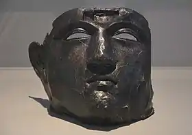 Vue d'un masque en bronze de forme humaine, auquel il manque la chevelure.