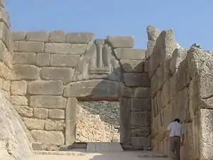 photographie couleurs : des murs formés d'énormes blocs de pierre, une porte dont le linteau est orné de lions affrontés