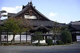 Wooden building with white walls and hip-and-gable style roof.